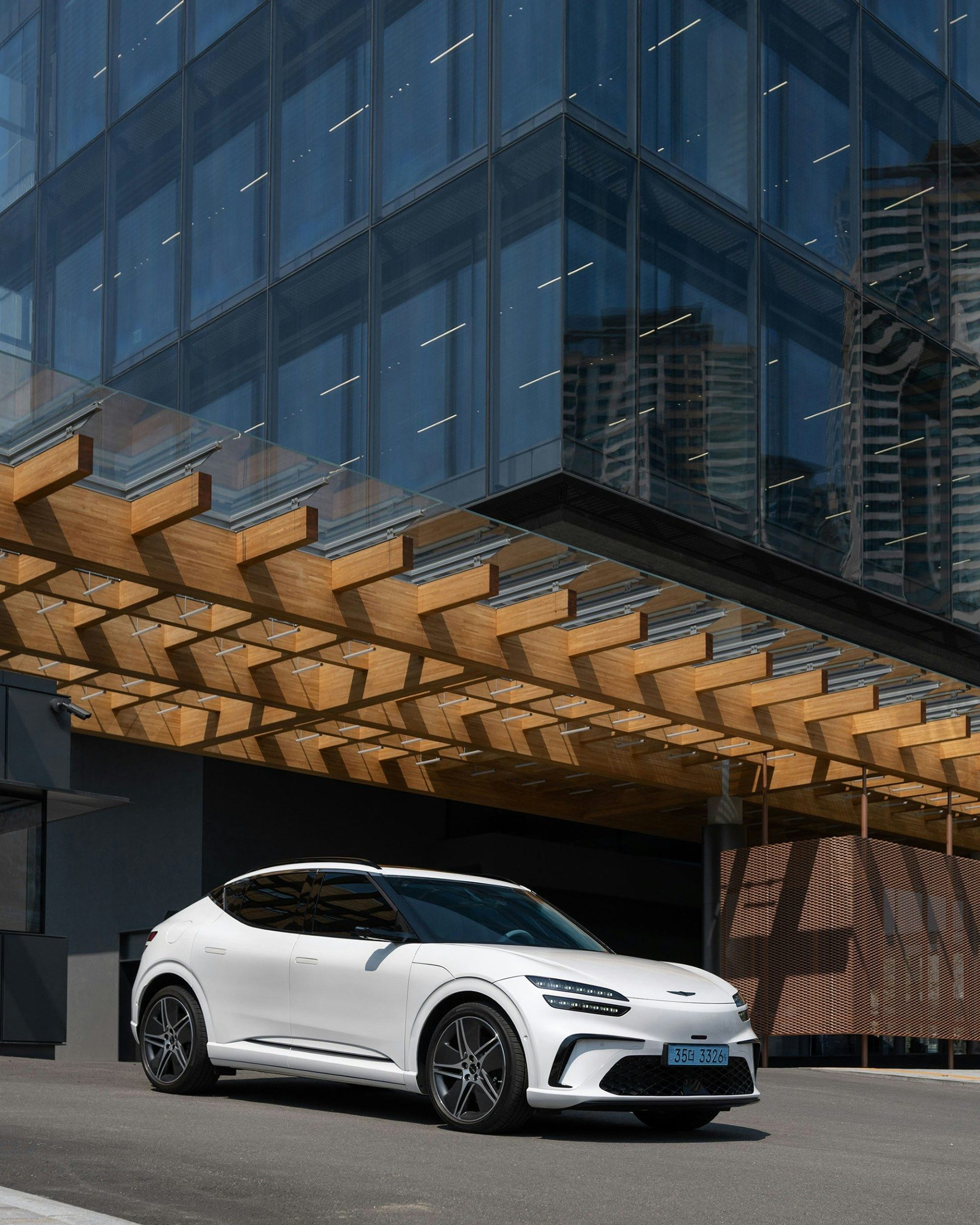 Ein weißer SUV steht unter einem modernen Gebäude.